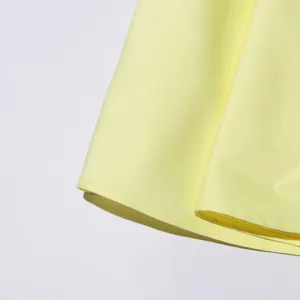 Elegant yellow dress fabric detail, fine stitching, smooth texture, chic summer style.