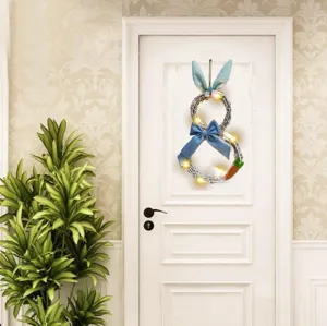 Detalle corona conejo Pascua, guirnalda ramas blanca con lazo azul y luces LED cálidas.