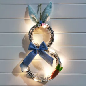 Primer plano de corona de ratán de conejito de Pascua con lazo azul y luces LED.