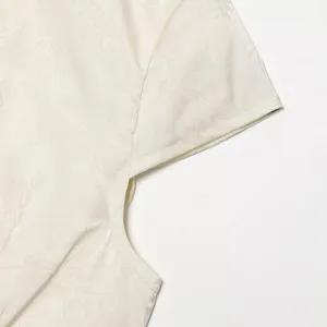 Dettaglio della manica dell'abito corto écru, elegante trama in tessuto jacquard.