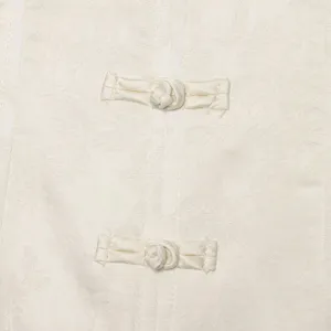 Primo piano dettagliato di tessuto jacquard bianco e bottoni cinesi tradizionali sull'abito.
