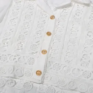 Close up detail of white lace embroidered lapel blouse with metallic nautical buttons.