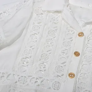 Detailed view of white lace shirt, featuring delicate hollow patterns and stylish gold buttons.