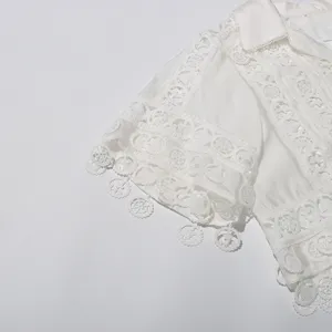 White lace embroidered blouse sleeve detail, delicate hollow out fabric with hanging charms.
