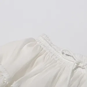 Close up of white lace trim shirred drawstring waist apparel detail, soft fabric texture design.