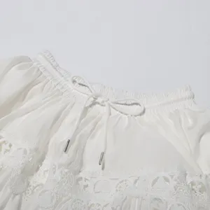Detailed view of white pleated skirt waist with delicate lace embroidery and adjustable drawstring.