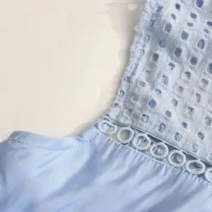 Gros plan détaillé de la robe sans manches bleu clair avec broderie anglaise et découpes.