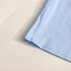 Gros plan détail robe bleu clair, texture tissu lisse, couture fine et délicate.
