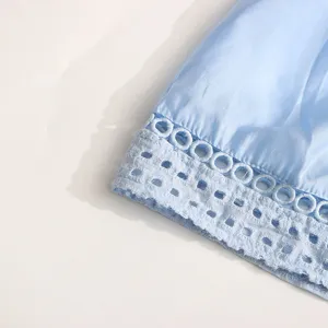 Gros plan détaillé de l'ourlet d'une robe bleu clair avec un délicat design de broderie anglaise.