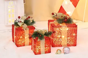 Ensemble de boîtes cadeaux de Noël illuminées avec rotin rouge et nœuds dorés.