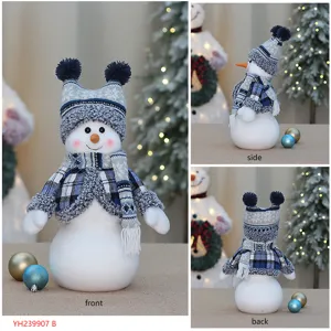 Vue détaillée de la poupée bonhomme de neige de Noël avec écharpe à carreaux et bonnet duveteux.