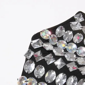 Close-up detail of sparkling faceted rhinestones and crystals embellished on black fabric.