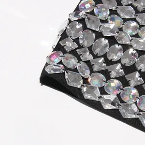 Close-up detail of luxury rhinestone crystal chain embellishment on black stretch fabric top.