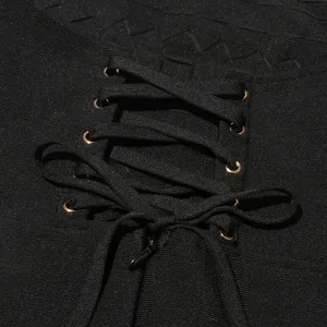 Close-up detail of black bandage dress featuring lace-up cross straps and metallic eyelets.