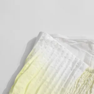 Close-up detail shot of gradient light yellow and white pleated strapless dress fabric.