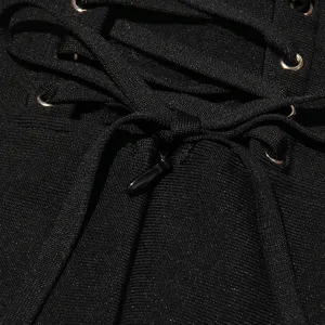 Close-up detail of black bandage dress showing metal eyelets, lacing, and zipper accent.