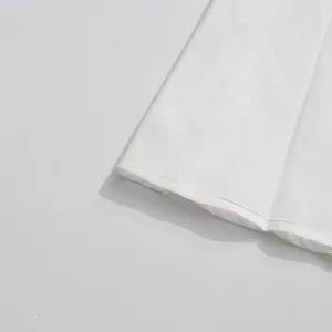 White dress fabric hem detail close-up showcasing fine stitching and smooth texture quality.