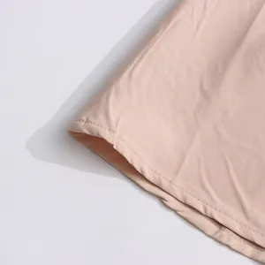 Pink dress fabric hem detail, fine stitching close-up, soft textile material display.