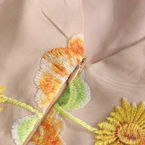Charming floral embroidery detail on lightweight mesh dress fabric for stylish summer wear.