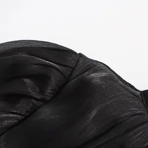 Gros plan détaillé du tissu plissé métallique noir, montrant une texture et un éclat exquis.