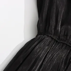 Gros plan sur la robe plissée métallisée noire, design élégant à la taille, tissu raffiné.