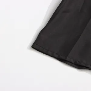 Vue rapprochée détaillée de l'ourlet en tissu métallique noir avec de fines coutures.