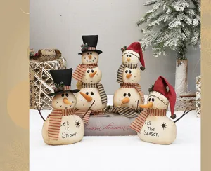 Primo piano dettagliato di pupazzi di neve in tessuto rustico con ricami e braccia di rami.
