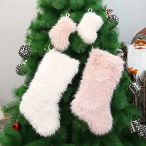 Fluffy pink and white plush Christmas stockings detail displayed on a festive tree backdrop.