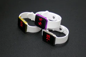 Square LED digital watch detail, white silicone strap, colorful metal case close-up view.