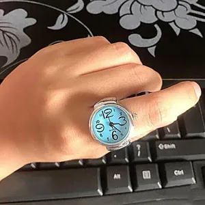 Closeup of a silver ring watch featuring a light blue dial with large numbers and quartz movement.