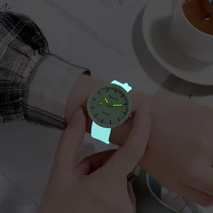Dettaglio di orologio al quarzo luminoso con lancette e cinturino in silicone al buio.