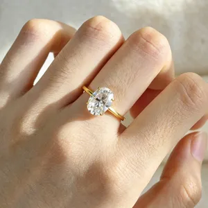 Gros plan sur la bague en moissonite ovale étincelante avec fine bande dorée.