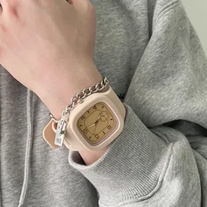 Nahaufnahme am Handgelenk: Beige Silikonuhr mit Metallkettenarmband und Anhänger.