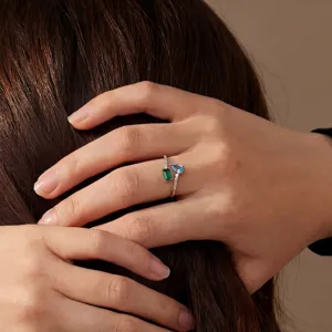 Gedetailleerde close-up van een stijlvolle zilveren ring met groene en blauwe zirkonia.