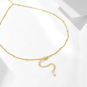 Gedetailleerde close-up van de goudkleurige satellietketting ketting met verlenging.