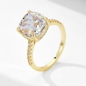 Close-up detail of cushion cut cubic zirconia ring with pavé band in gold finish.