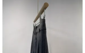 Detail shot of women's dark grey corduroy wide-leg trousers hanging on a wooden hanger.
