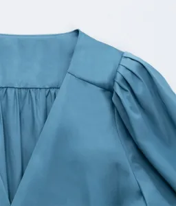 Vue détaillée de la robe en coton bleu avec col en V et plis d'épaule bouffants.