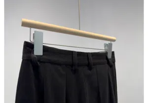 Corduroy trousers detail view showcasing black fine-ribbed fabric, waistband loops and texture.