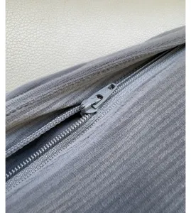 Grey corduroy trousers detail shot, showing textured fabric and metal zipper close-up.