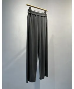 Detailed view of pleated wide-leg trousers in dark grey with elastic waist and soft drape.