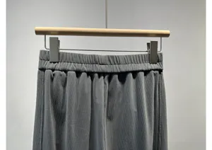 Grey corduroy pleated trousers detail shot showing elastic high waist and soft texture fabric.