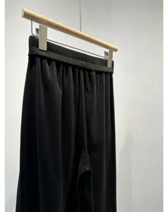 Black pleated wide leg trousers detail view, casual high waist design, soft drape fall.