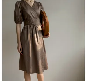 Gros plan sur les détails de la robe en coton à col en V et manches bouffantes.