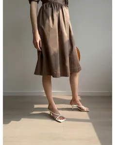Gros plan détaillé de l'élégante robe marron en coton à manches bouffantes, texture premium.