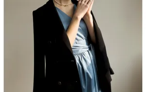 Gros plan détaillé d'un blazer élégant sur une robe bleu clair avec collier de perles.