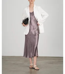 Elegante satijnen slipjurk gecombineerd met een witte blazer voor stijlvolle looks.