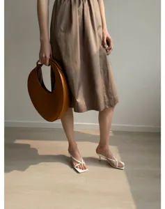 Élégante robe midi de style français associée à un sac à main croissant tendance.