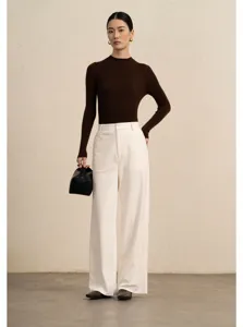 Detailed view of white corduroy wide-leg trousers styled in casual autumn outfit.