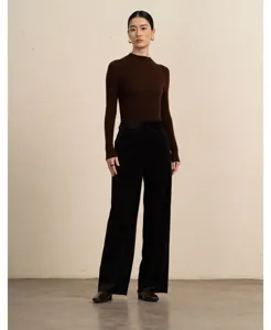 Full length view of a woman wearing brown knit top and black corduroy wide leg pants.
